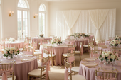 bright event room features multiple round tables with dusty pink tablecloths