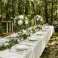 Two olive-green French Toile scalloped-edge placemats on a white table with gold cutlery and floral centerpiece.