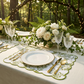 Olive green French Toile scalloped-edge placemats on a garden table with white plates and crystal glasses.