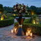 38" Tall Hourglass Plinth Pedestal Stand Black outside with vase of mixed floral and candles in a garden