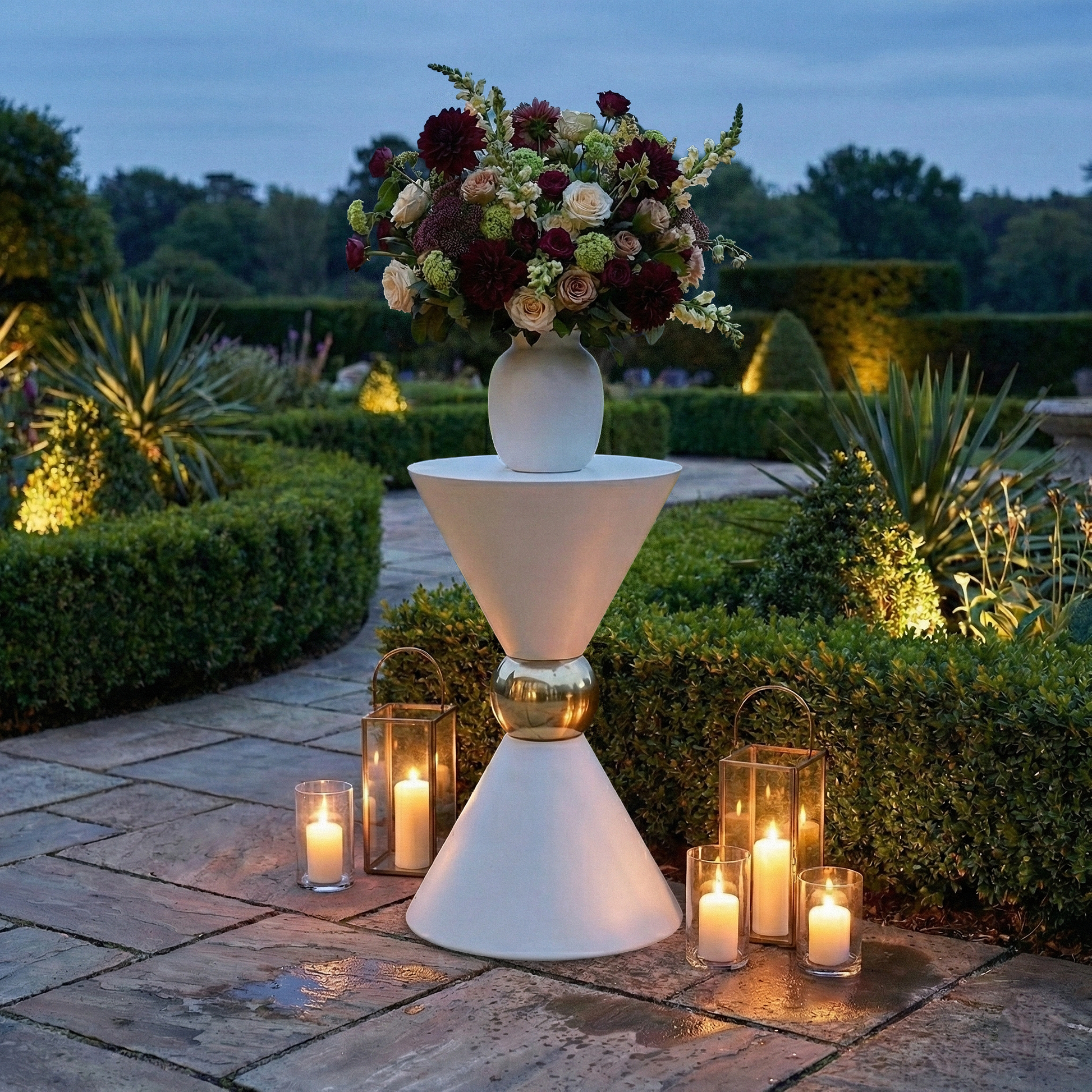 38" Tall Hourglass Plinth Pedestal Stand White outdoor garden set up with gold pillar candles, and a vase of mixed florals
