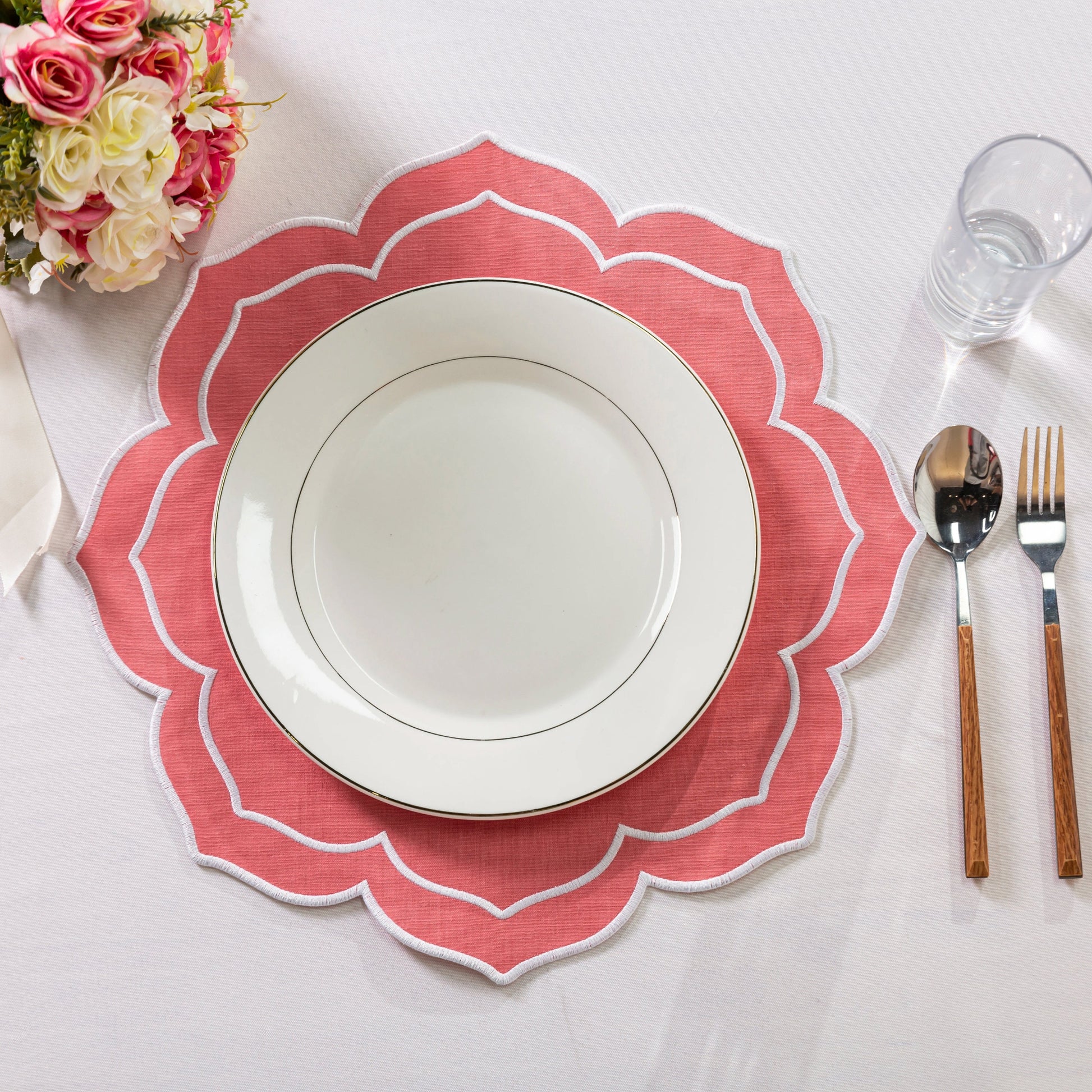 4pc/set Petal Elegance Placemats - Coral/White Trim paired with a white tablecloth, white dinner plate, florals and silverware