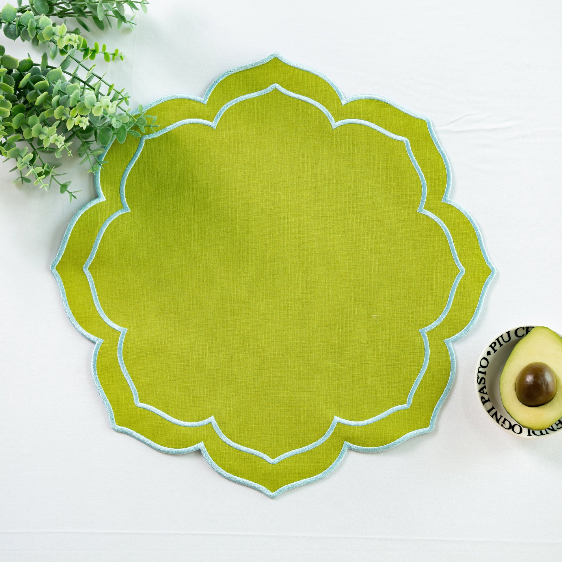 4pc/set Petal Elegance Placemats - Matcha/Turquoise Trim paired with a white tablecloth, and faux greenery