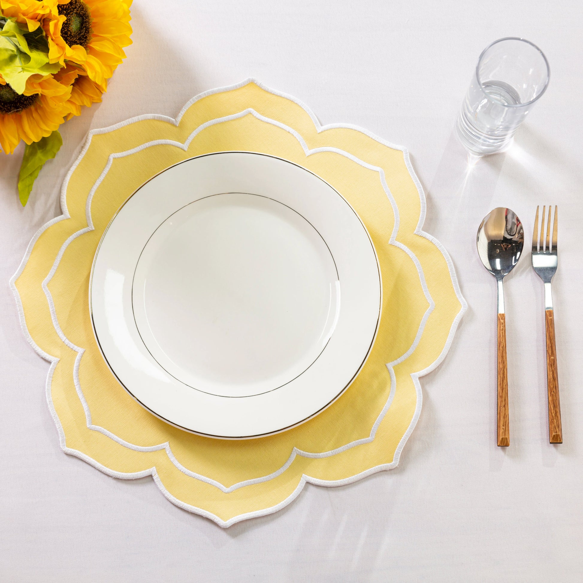 Petal Elegance Placemats - Pastel Yellow/White Trim with a white dinner plate, silverawre and water glass