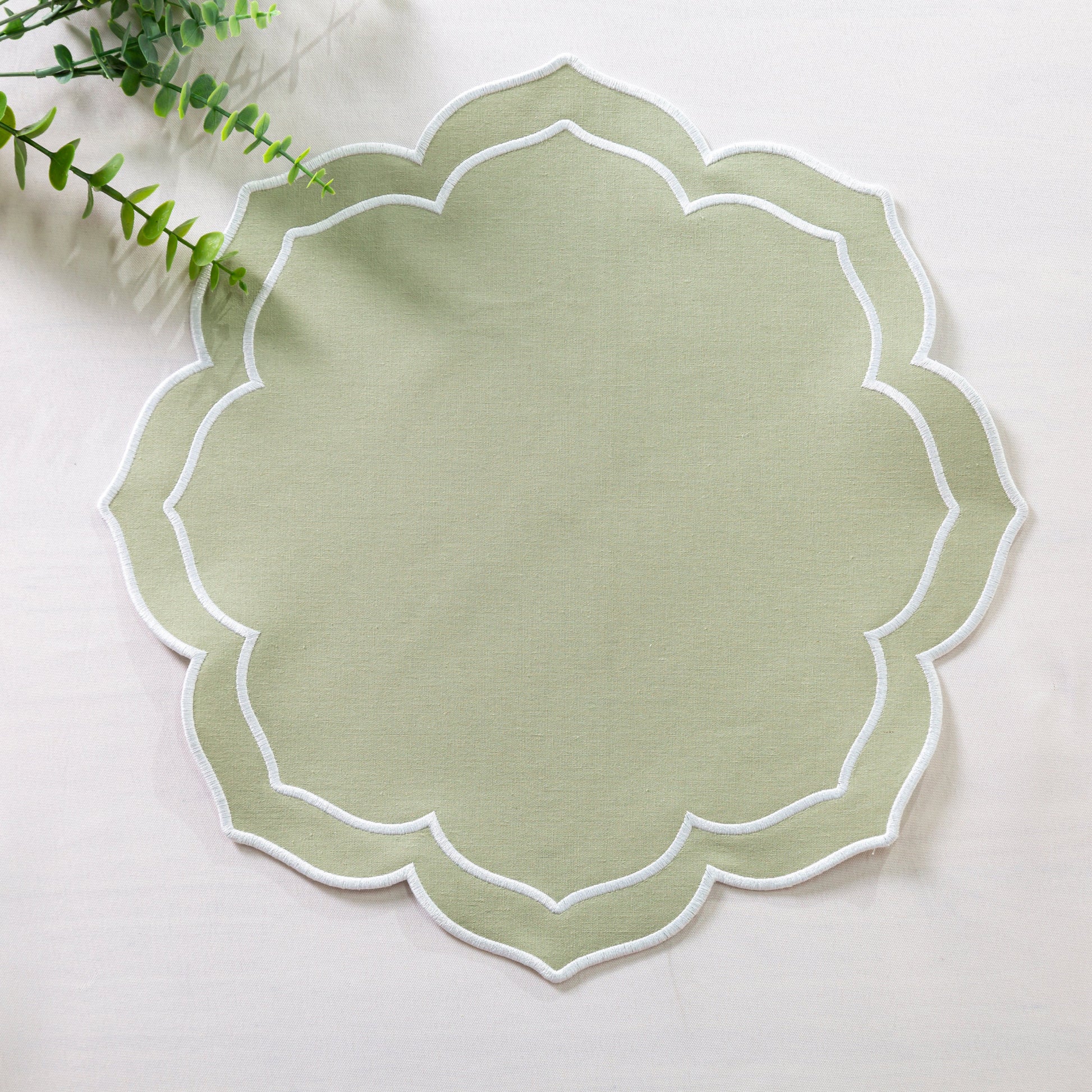 Petal Elegance Placemats - Sage Green/White Trim on top a white tablecloth with faux greenery