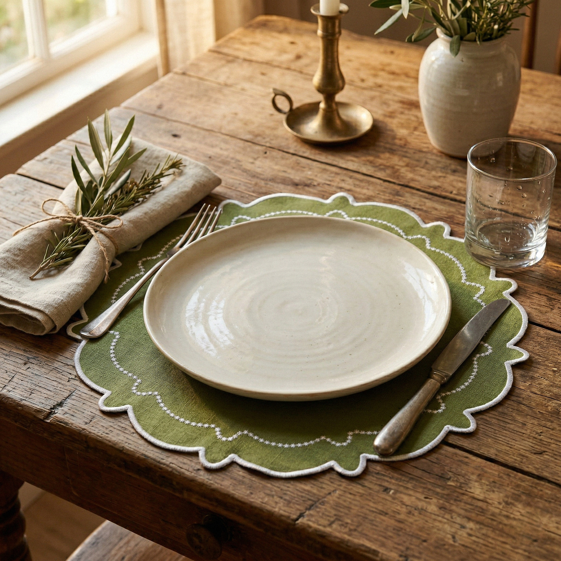 rustic theme with the 4pc/set Signature Scallop Placemats Olive Green/White Trim, burlap napkin with a sprig of rosemary, silverware, and a water glass
