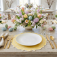 Easter table with 4pc/set Signature Scallop Placemats Pastel Yellow/White Trim, white dinner plate, colored easter eggs and pastel floral centerpieces