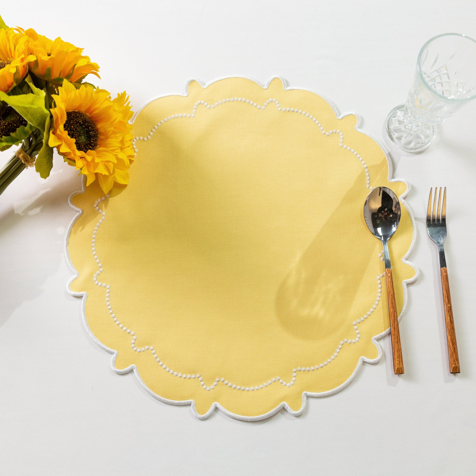 4pc/set Signature Scallop Placemats Pastel Yellow/White paired with sunflowers, silverware, and wine goblet