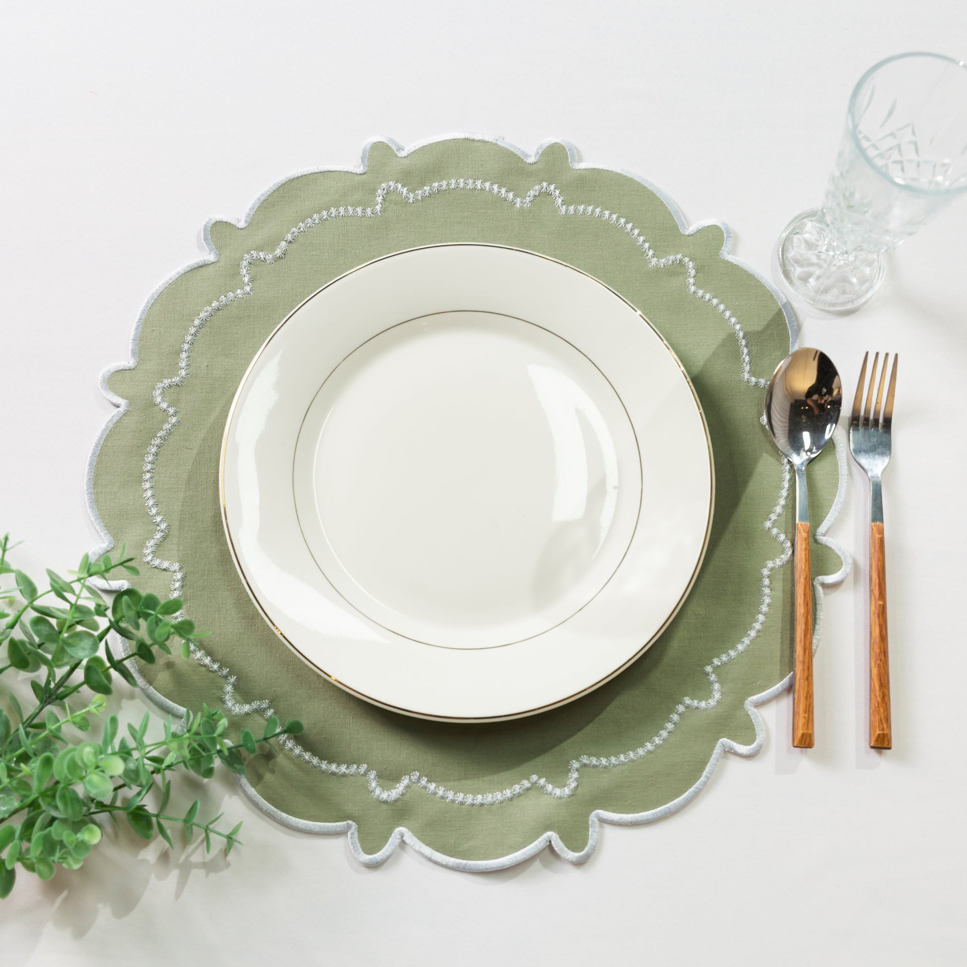 4pc/set Signature Scallop Placemats Sage Green/White Trim with a white dinner plates, faux greenery and silverware