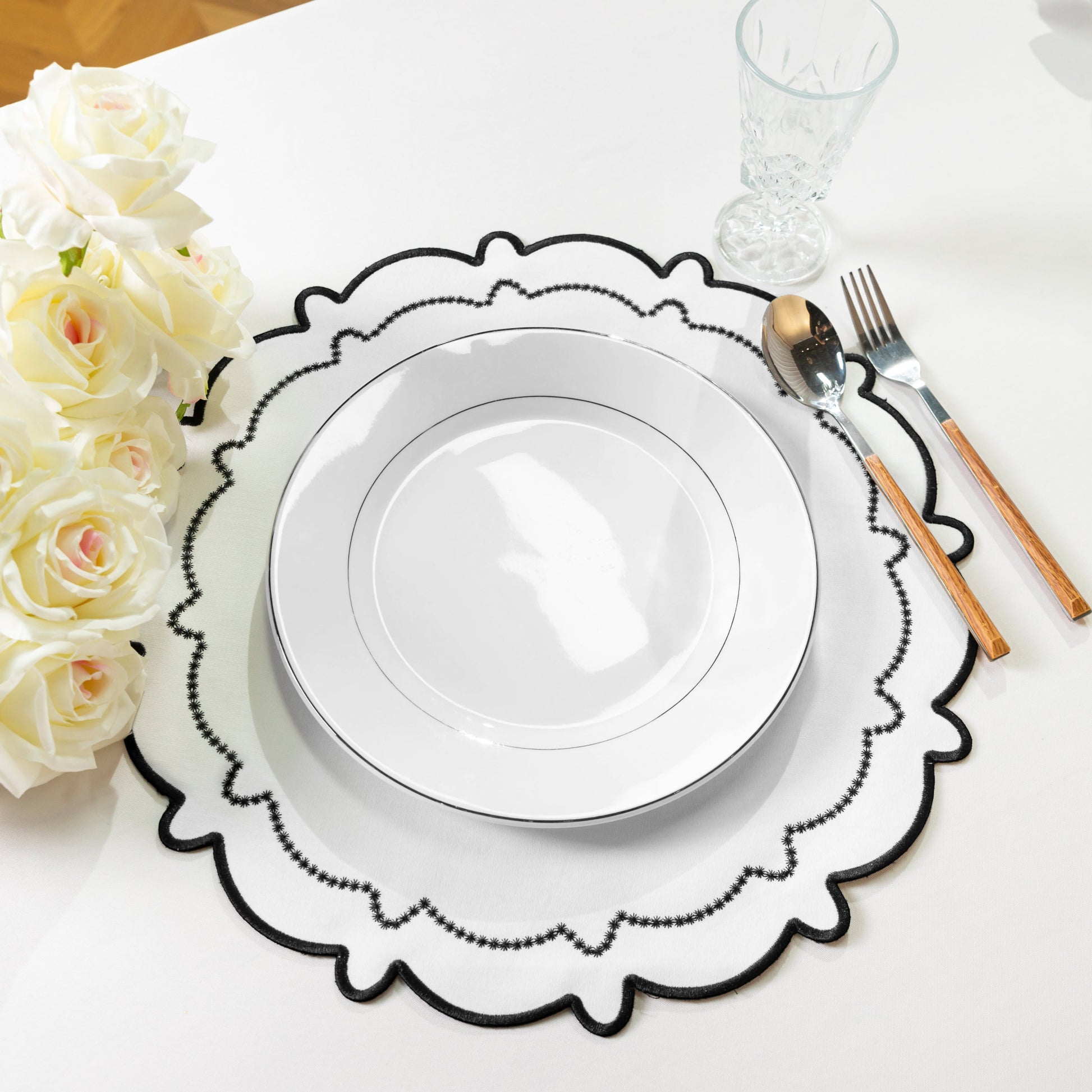 4pc/set Signature Scallop Placemats - White/Black Trim with white dinner plate, ivory roses, and silverware