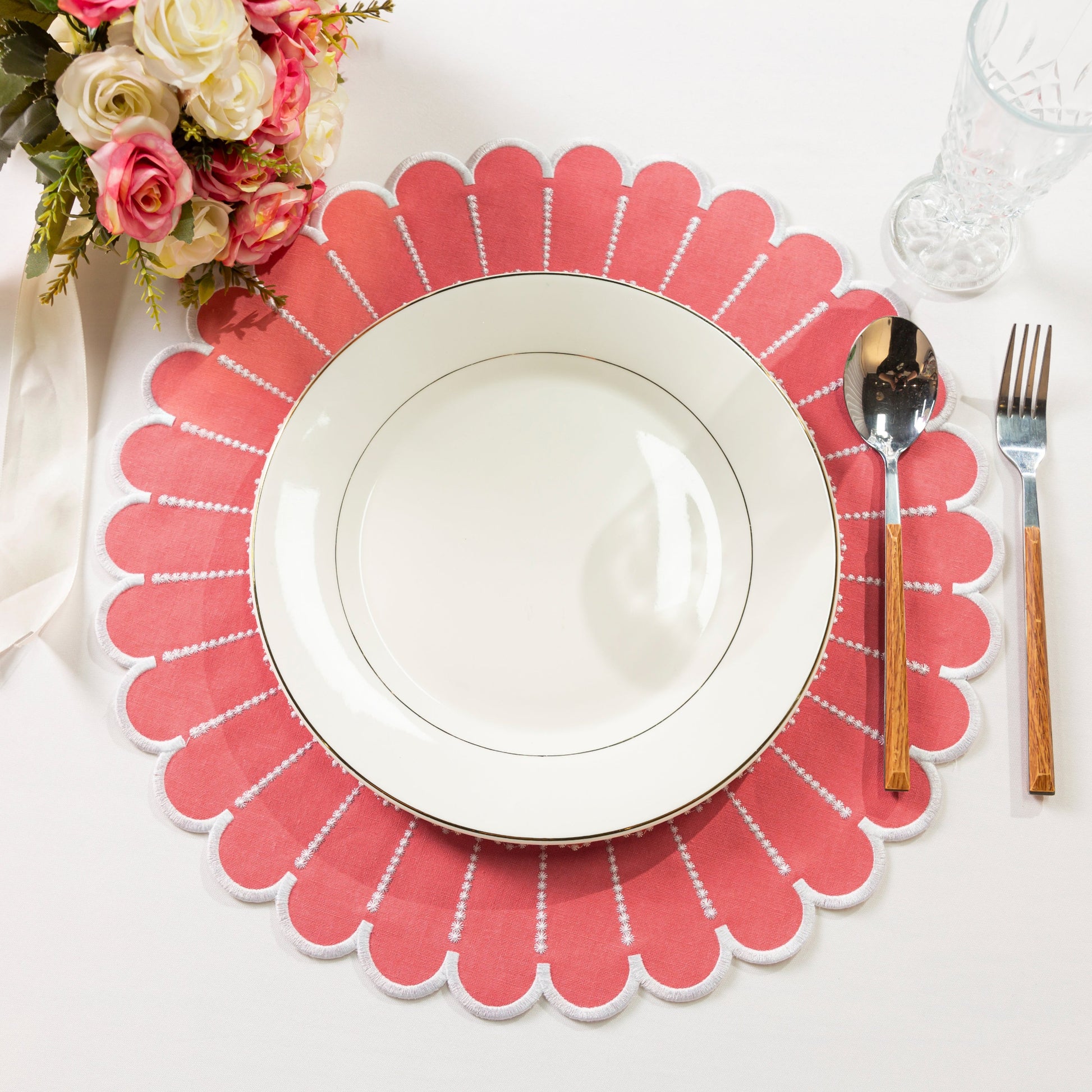 4pc/set Sunburst Edge Placemats Coral/White Trim paired with white dinner plate, florals, silverware on a white tablecloth