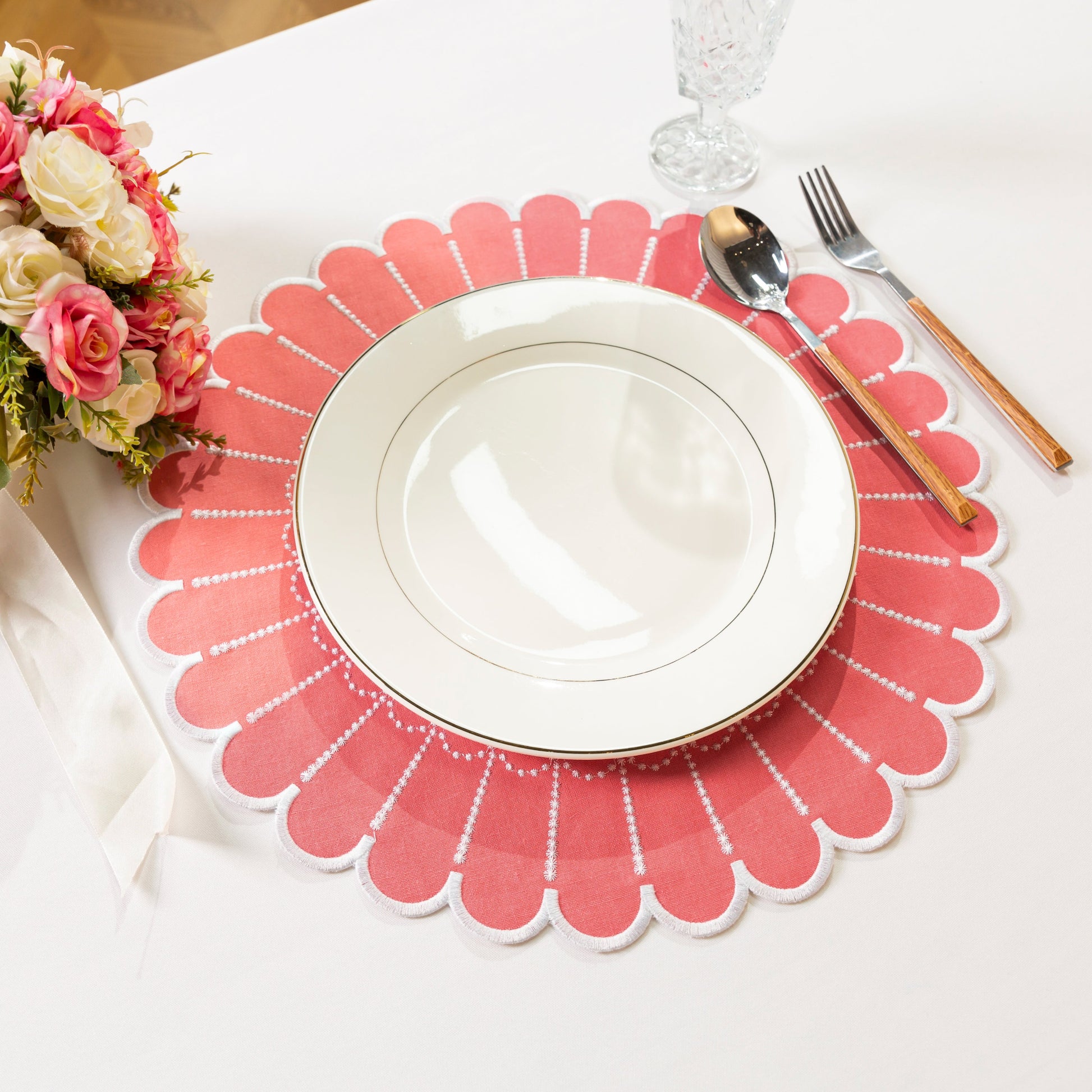 4pc/set Sunburst Edge Placemats Coral/White Trim paired with white dinner plate, florals, silverware on a white tablecloth