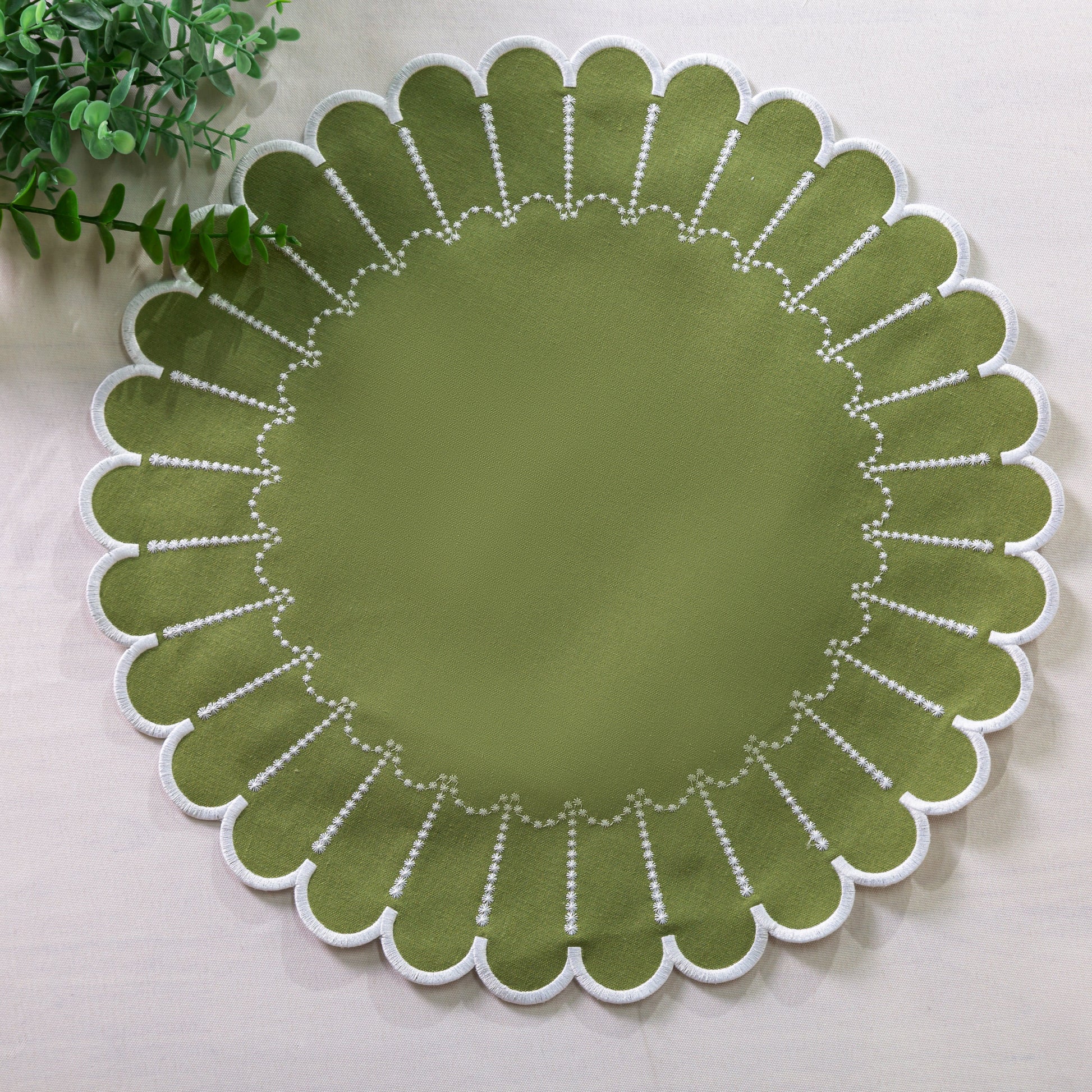 4pc/set Sunburst Edge Placemats Olive Green/White Trim paired with faux greenery on a white tablecloth