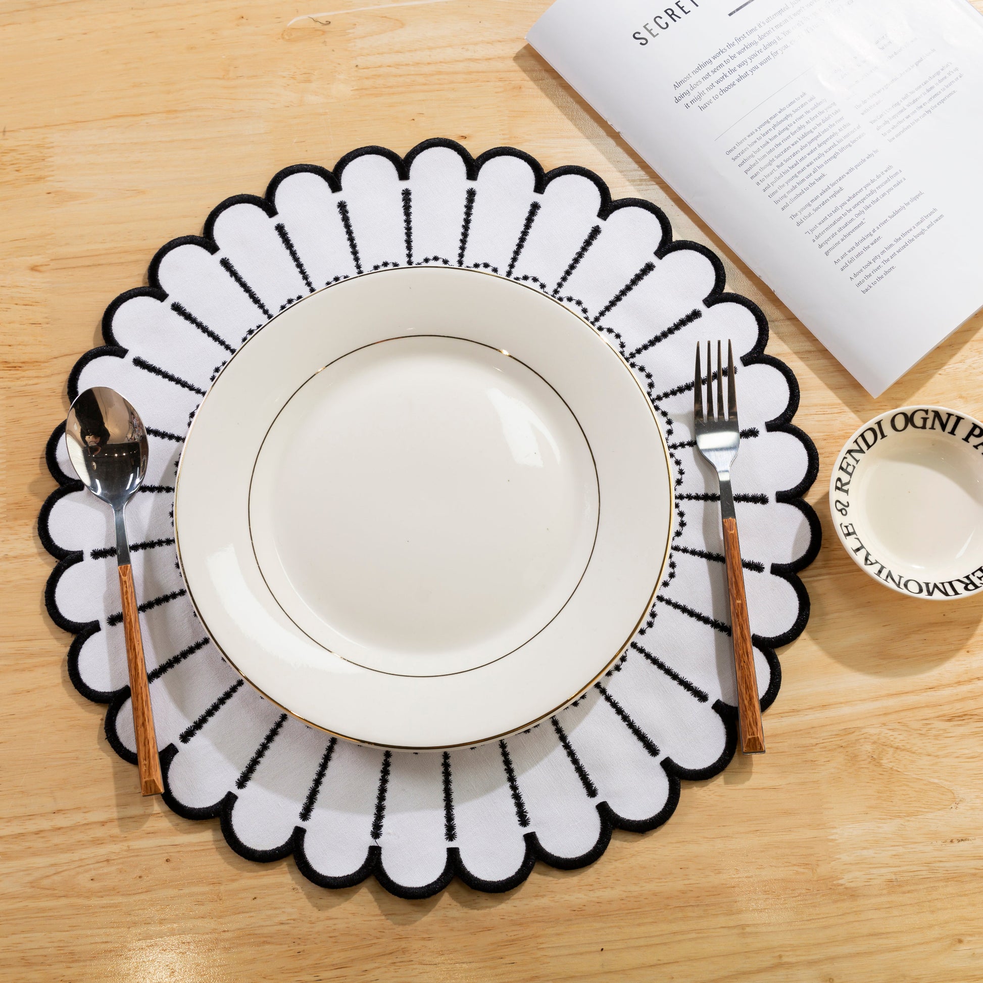 4pc/set Sunburst Edge Placemats White/Black Trim paired with white dinner plate, and silverware