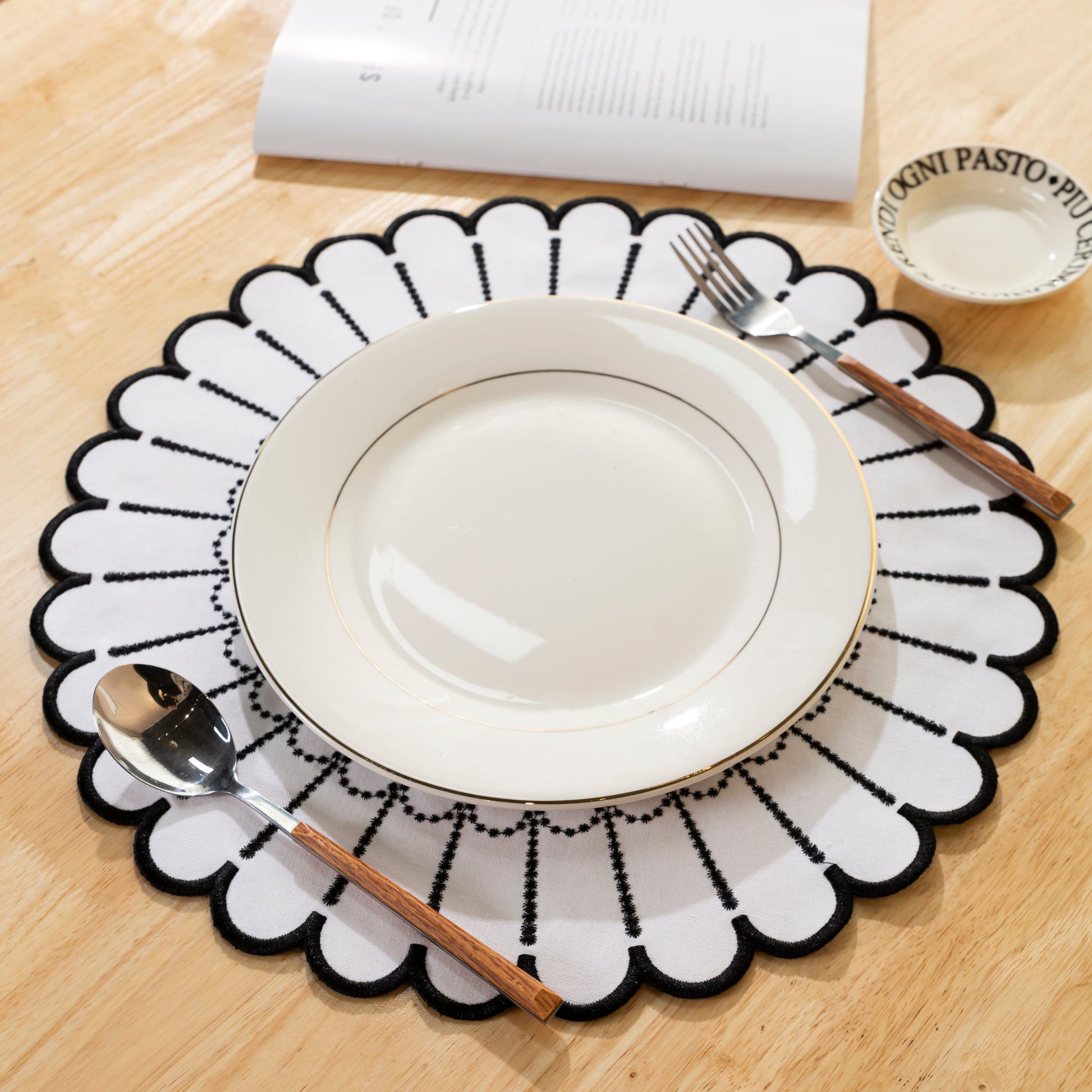 4pc/set Sunburst Edge Placemats White/Black Trim paired with white dinner plate, and silverware