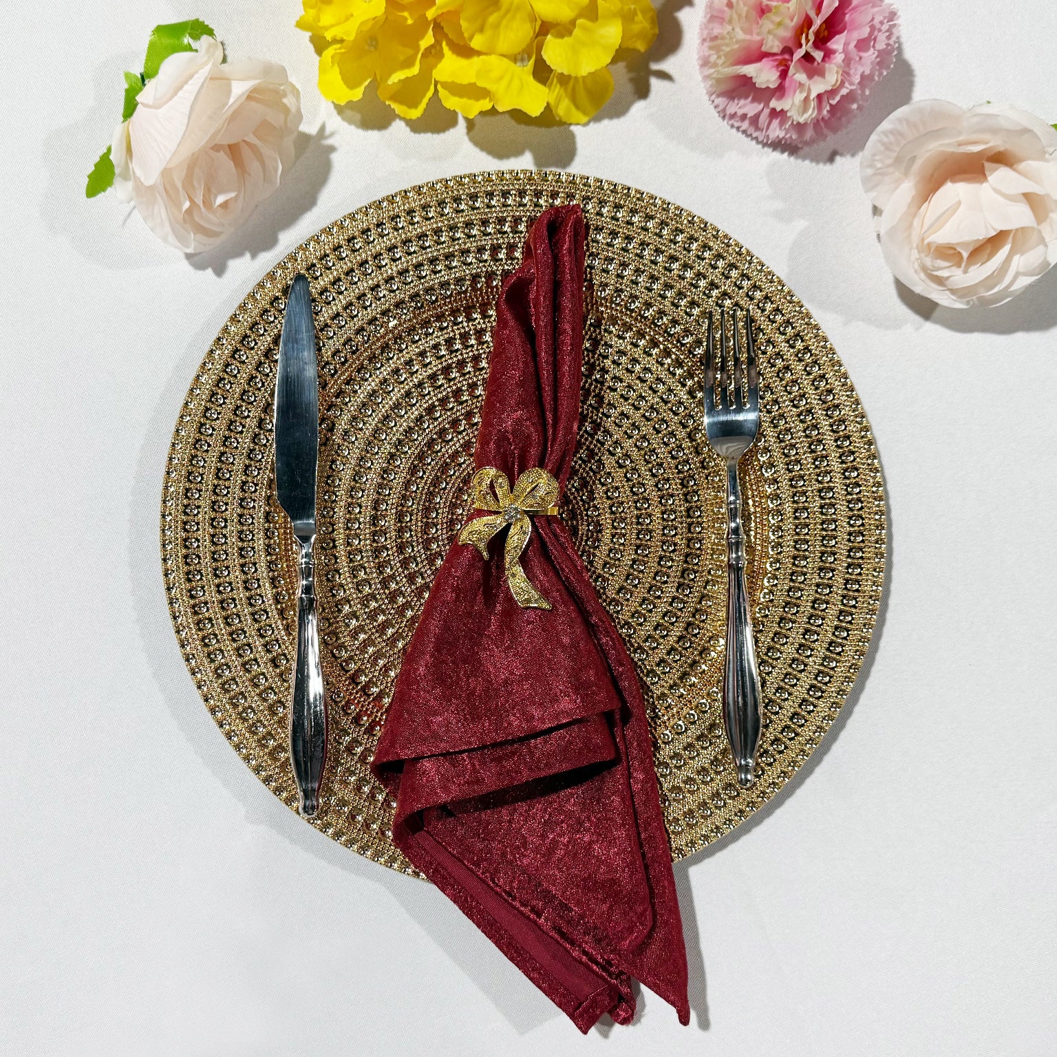 Crinkle Shimmer Napkin 20"x20" - Burgundy folded with a gold bow napkin ring, gold charger plate and silverware