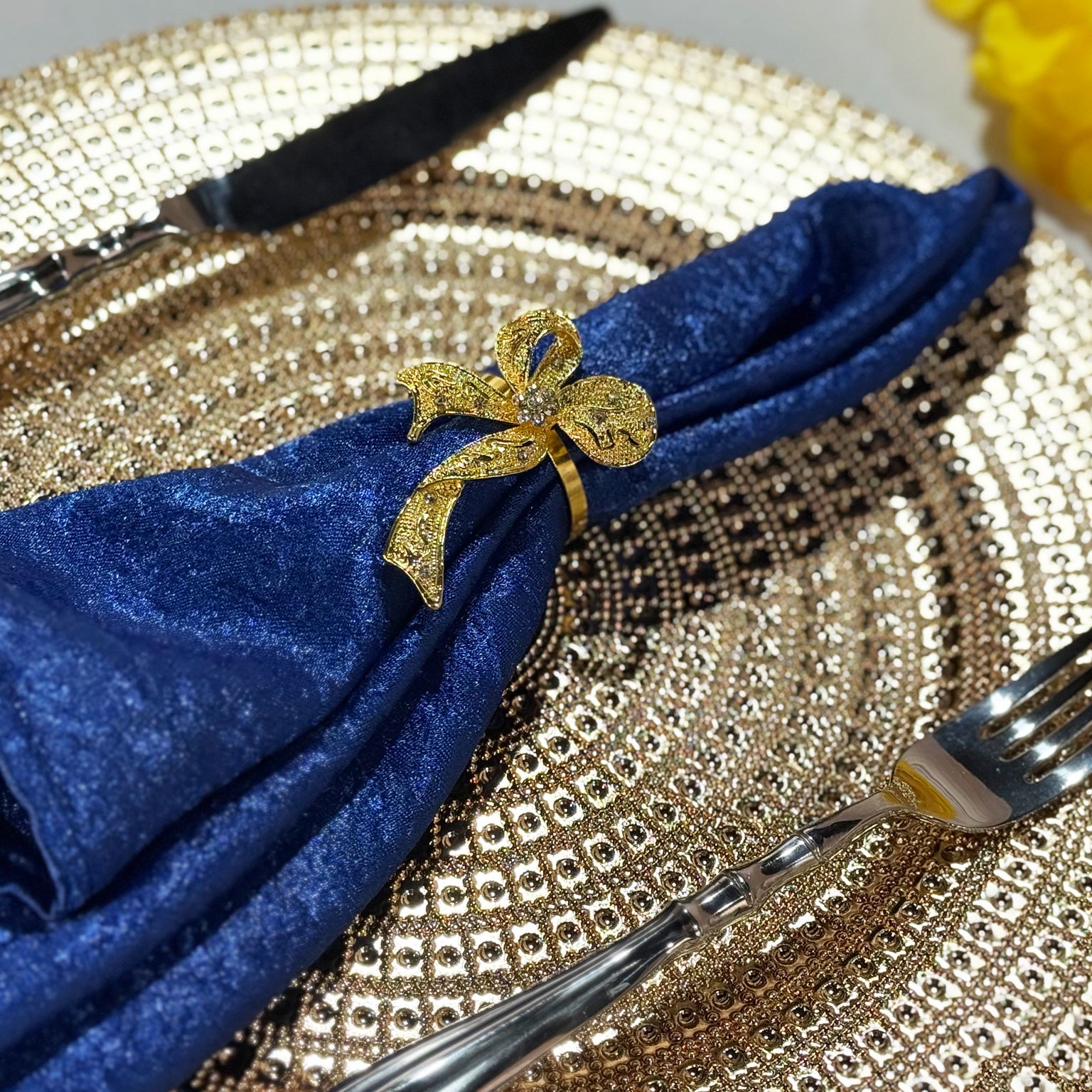 5 pcs/pk Crinkle Shimmer Napkin 20"x20" Royal Blue fold napkin with a gold bow napkin ring on a gold charger plate close up