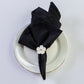 5 pcs/pk Embossed Geometric Jacquard Napkin 20"x20" Black fan fold with a white flower napkin ring on top a white dinner plate