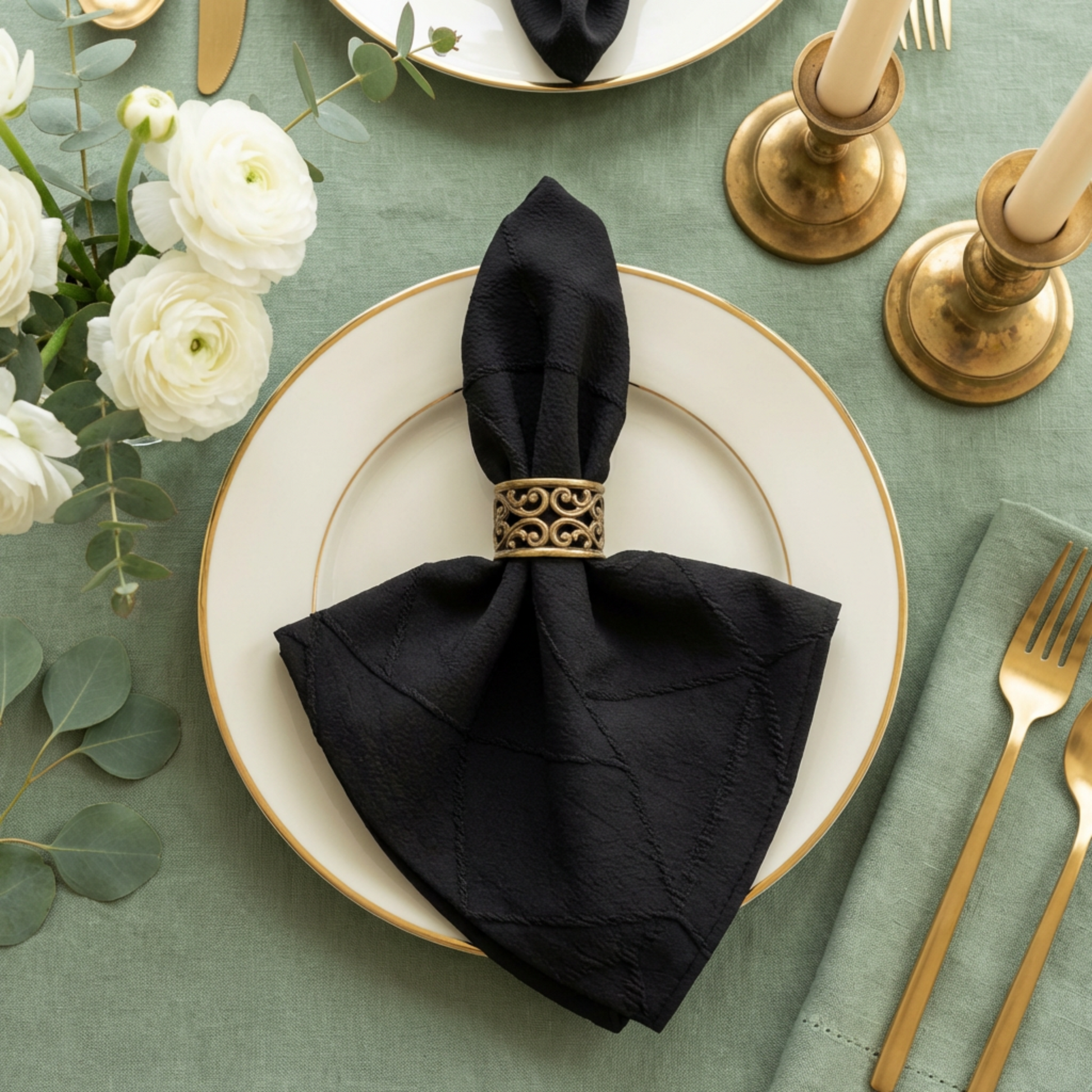 Embossed Geometric Jacquard Napkin 20"x20" Black paired with a gold napkin ring, on top a dinner plate and sage green tablecloth