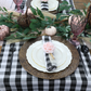 5 pcs/pk Gingham Checkered Polyester Napkin 20"x20" Black & White with a pink flower ring on top of ivory dinner plates, faux rattan charger plate and gingham checkered table runner