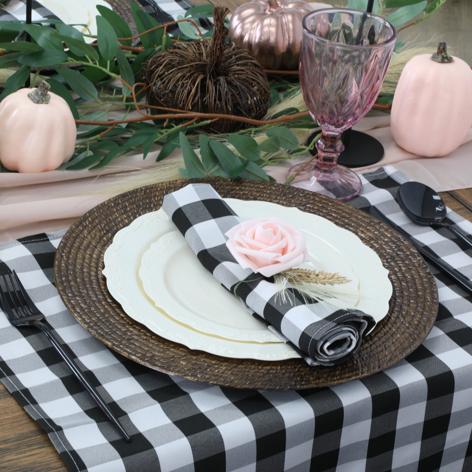 5 pcs/pk Gingham Checkered Polyester Napkin 20"x20" Black & White with a pink flower ring on top of ivory dinner plates, faux rattan charger plate and gingham checkered placemats, blush goblets, faux greenery garland