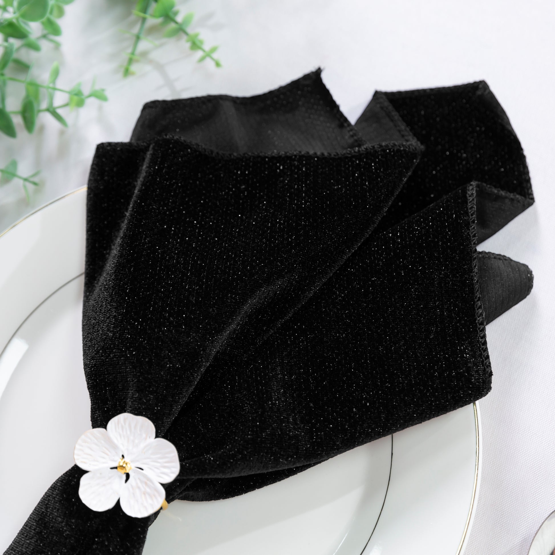 5 pcs/pk Glitter Velvet 20"x20" Linen Napkin Black close up of the napkin on a white charger plate and white flower napkin ring