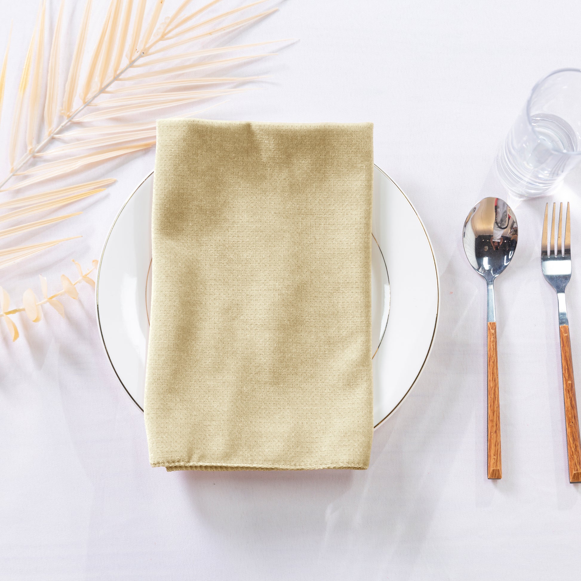 5 pcs/pk Glitter Velvet 20"x20" Linen Napkin Champagne folded on top of a white charger plate