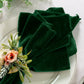5 pcs/pk Glitter Velvet 20"x20" Linen Napkin Emerald Green paired with a white charger plate, and faux floral napkin ring