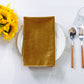 5 pcs/pk Glitter Velvet 20"x20" Linen Napkin Gold folded on a white charger plate, sunflowers and silverware