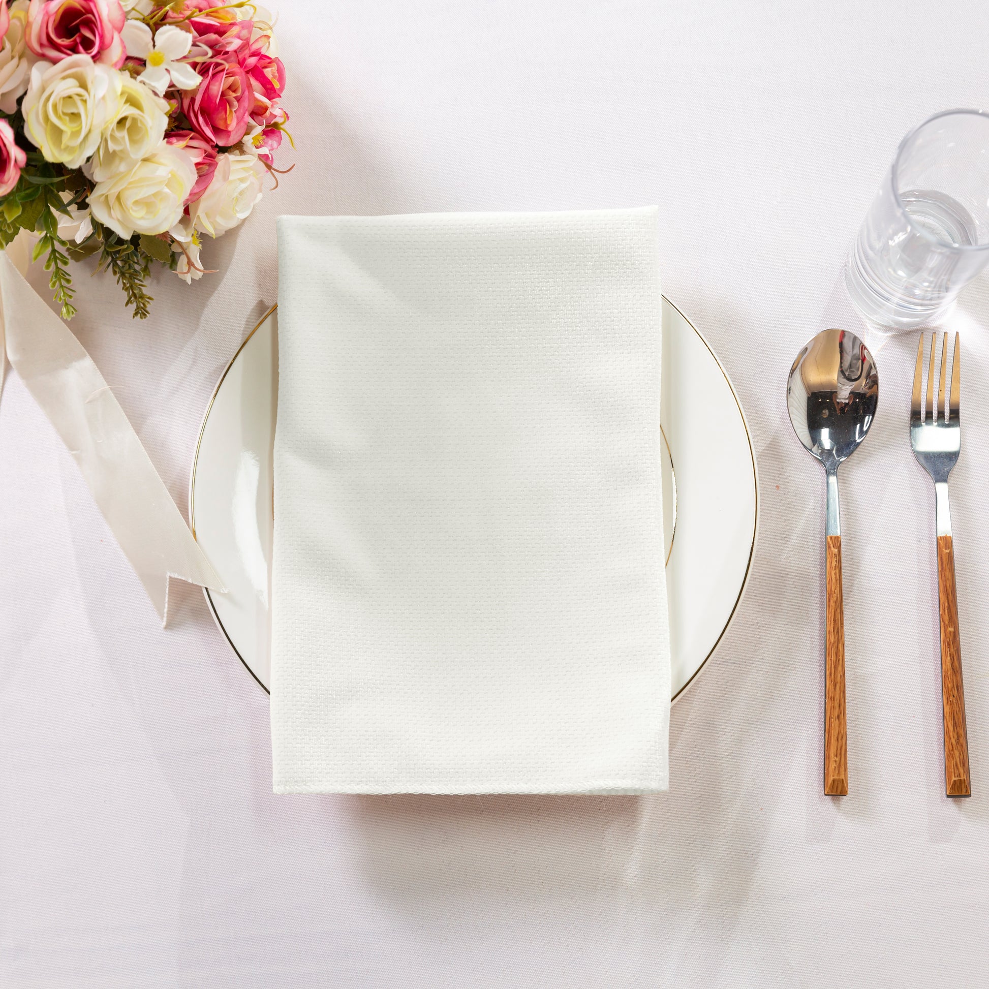 5 pcs/pk Glitter Velvet 20"x20" Linen Napkin Ivory paired folded on a white charger plate, florals and silverware