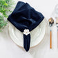 5 pcs/pk Glitter Velvet 20"x20" Linen Napkin Navy Blue paired with a flower napkin ring, white charger plate, faux greens and silverware