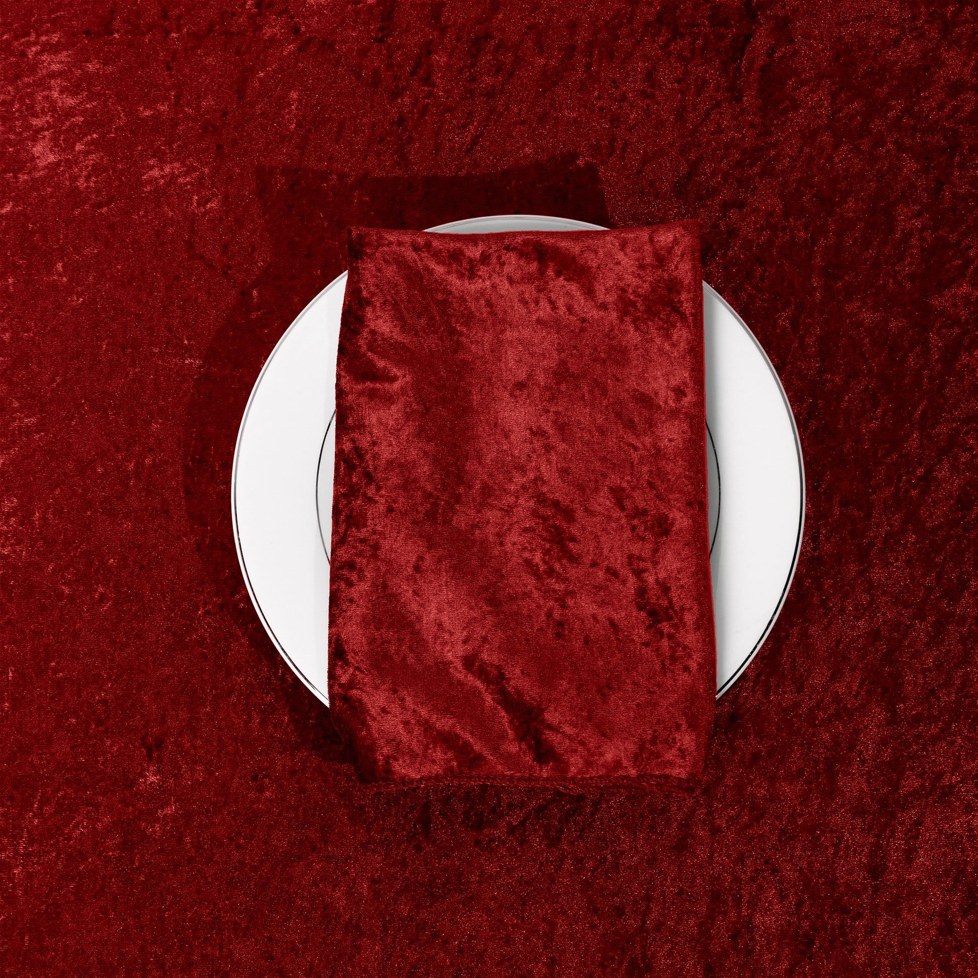Velvet 20"x20" Linen Napkin Apple Red folded on a charger plate on top of a apple red velvet tablecloth
