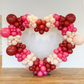 red, pink and white balloons on the  6.5ft Heart Frame Arch Backdrop against a white wall background