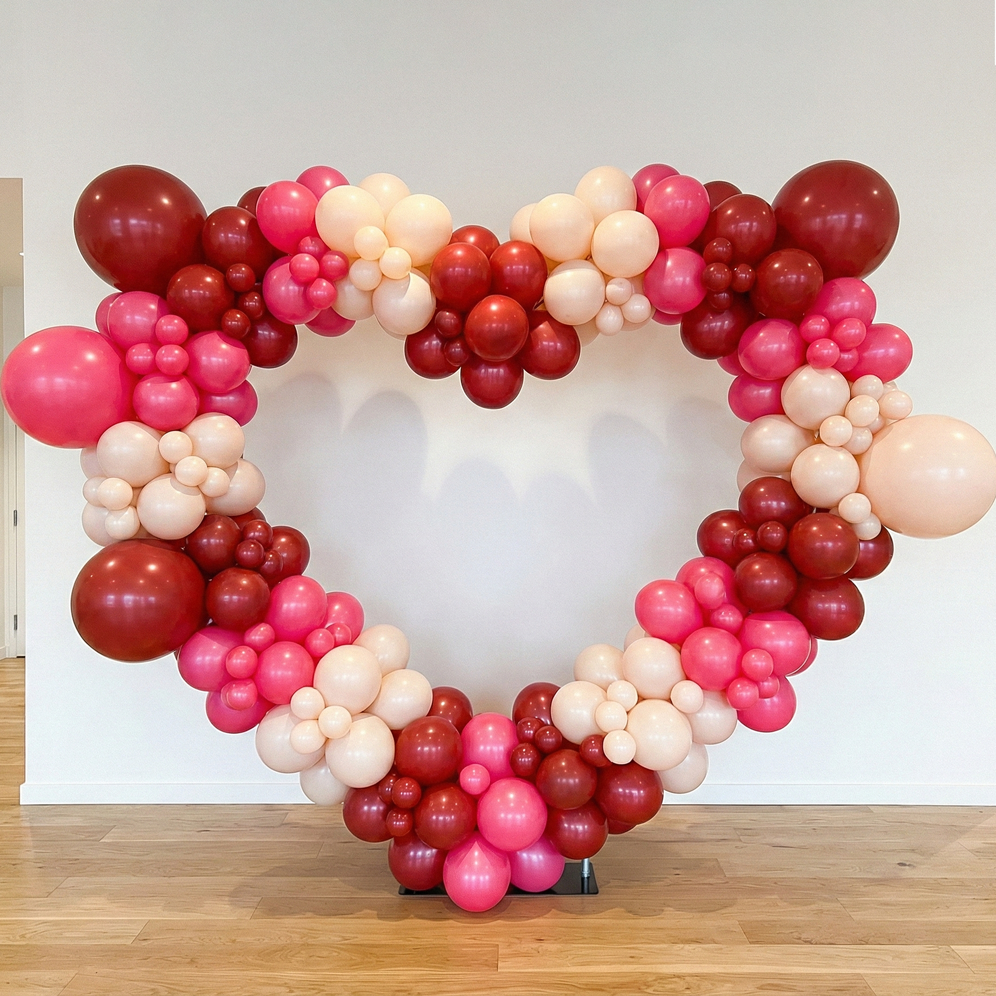 red, pink and white balloons on the  6.5ft Heart Frame Arch Backdrop against a white wall background