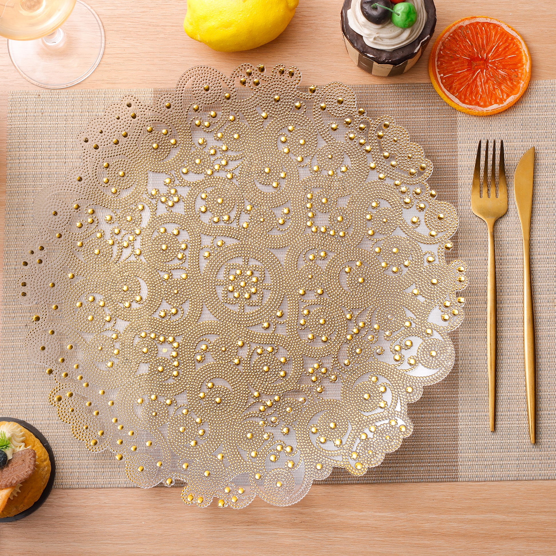 Filigree Acrylic Charger Plate Gold on top a placemat with gold flatware and desserts