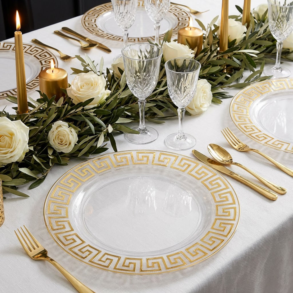 8 pc/set Greek Key Acrylic Charger Plate Clear Gold Trim on top a white tablecloth with gold flatware and greenery table runner