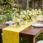 Velvet Table Runner Canary Yellow with yellow and white floral centerpieces in an outdoor setting 