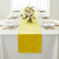 Velvet Table Runner Canary Yellow on top a white rectangular tablecloth with water goblets, white dinner plates and floral centerpiece
