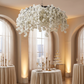 Cherry Blossom Ceiling Cascade White hanging above the 48" round table with white tablecloth, gold candle holders and champagne flutes