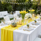 outdoor gathering table set up with the Chiffon Wedding Table Runner 10FT x 27" Canary Yellow, marble placemats, yellow tulip centerpieces, wine goblets, and gold silverware