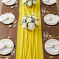 table setting with the Chiffon Wedding Table Runner 10FT x 27" Canary Yellow, white dinner plates, floral centerpieces, gold silverware and wine goblets
