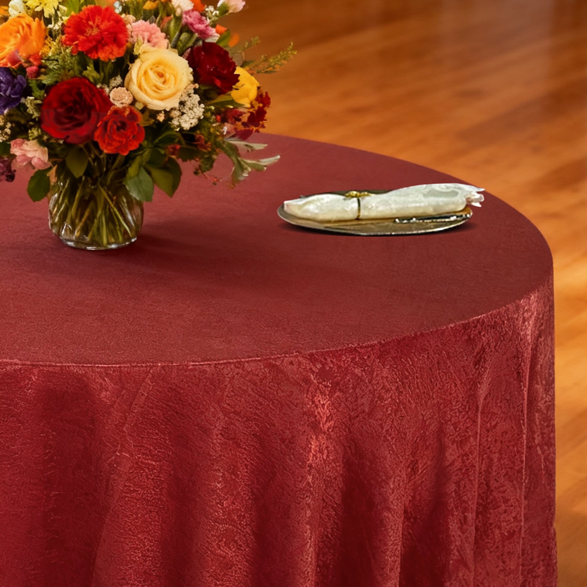 Crinkle Shimmer 132" Round Tablecloth Burgundy with floral centerpiece, gold charger plate and ivory napkin