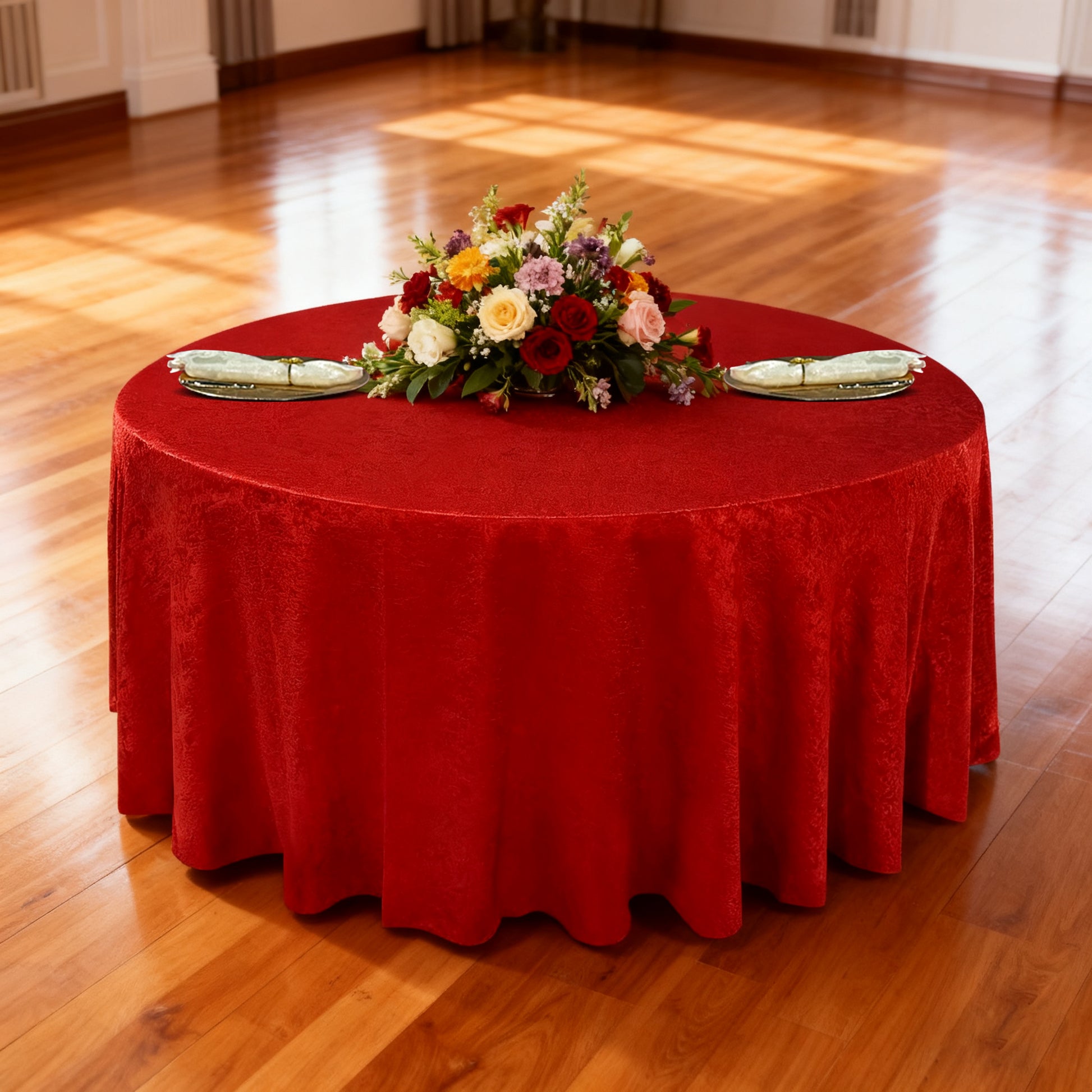 Crinkle Shimmer 132" Round Tablecloth Red table setting with floral centerpiece, gold charger plates and ivory napkins