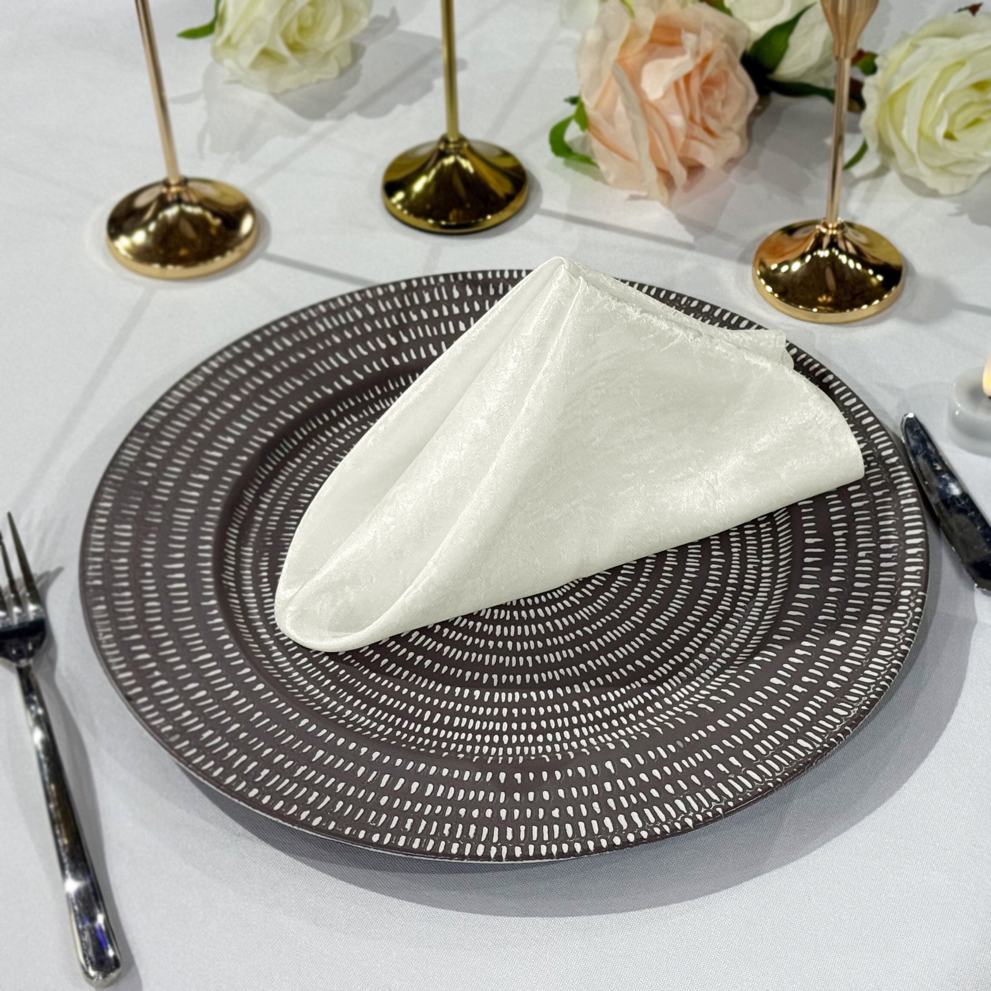 5 pcs/pk Crinkle Shimmer Napkin 20"x20" - Ivory on top a charger plate and silverware