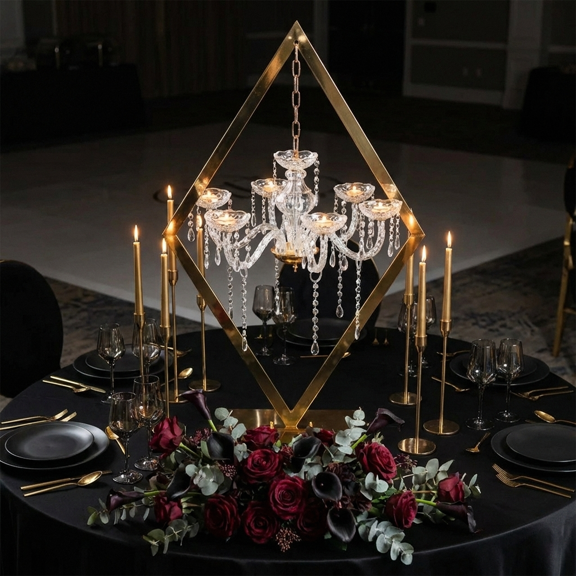 Diamond Shape Centerpiece with Hanging Chandelier Gold paired with black satin round tablecloth, red and black florals, black dinner plates and gold silverware