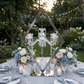 outdoor reception table with the Diamond Shape Centerpiece with Hanging Chandelier Silver, blue and white floral centerpieces, and wine glasses