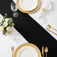 Embossed Geometric Jacquard Table Runner Black  overview on top a white tablecloth with gold charger plates, and gold silverware