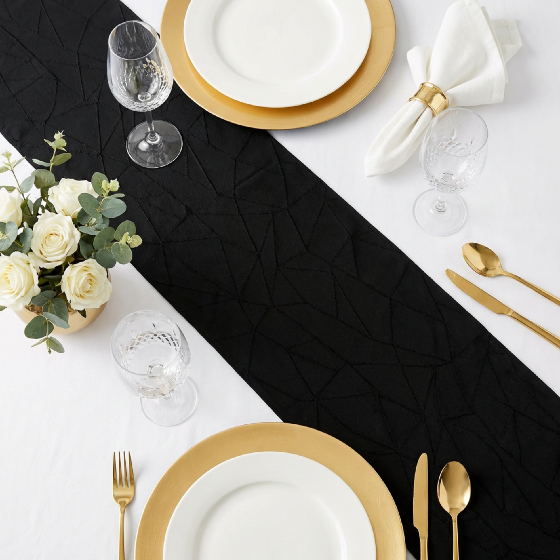 Embossed Geometric Jacquard Table Runner Black  overview on top a white tablecloth with gold charger plates, and gold silverware