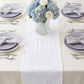 Embossed Geometric Jacquard Table Runner White on top an ivory tablecloth, gray charger plates, and gray/silver polyester napkins