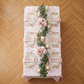 birds eye view of the French Toile 90"x132" Rectangular Tablecloth Dusty Rose/Mauve table setting with blush napkins, gold silverware, white/gold dinner ware and geenery table runner